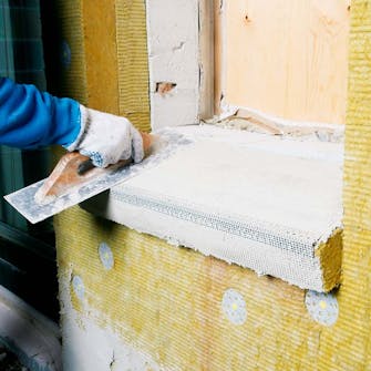 Udvendig isolering: Grundpudsemørtel på sålbænk Udvendig isolering: Grundpudsemørtlen trækkes ud over sålbænken